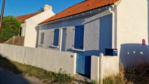 A white building with a red-tiled roof, blue shutters, and a number '22' sign.