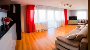 Un salon moderne avec un canapé, un téléviseur et un coin repas.