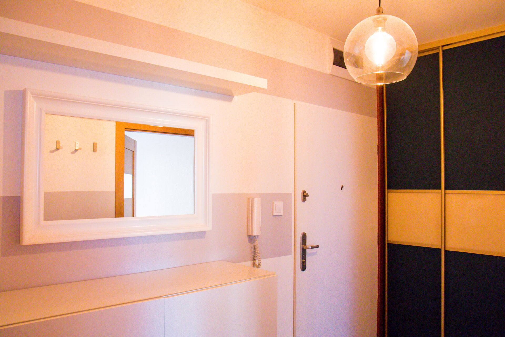 Casa de banho com espelho, porta-toalhas e uma porta com uma toalha pendurada.
