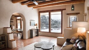 Uma sala de estar acolhedora com lareira, espaço para refeições e amplas janelas com vista para a paisagem nevada.