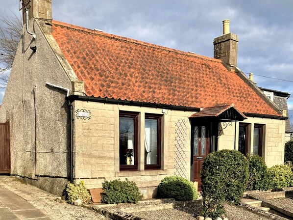 A stone building with a tiled roof, a wooden door, and a small garden with bushes. - Aultnagar pet friendly, 1 bedroom, sleeps 2, free WiFi near St Andrews Fife (Upper Largo)