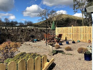 A patio with a stone wall, wooden fence, and outdoor furniture. - Aultnagar pet friendly, 1 bedroom, sleeps 2, free WiFi near St Andrews Fife (Upper Largo)