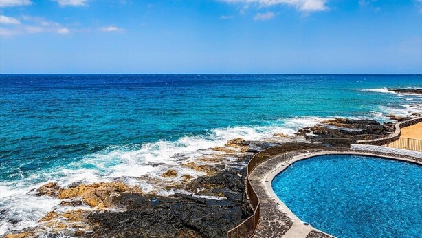 Une piscine avec vue sur l’océan et le littoral rocheux.