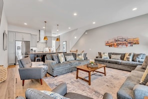 A spacious living area with a grey sofa set, a wooden coffee table, and a cityscape artwork on the wall.