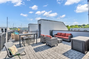 A rooftop terrace with outdoor furniture, a pool, and a view of the cityscape.