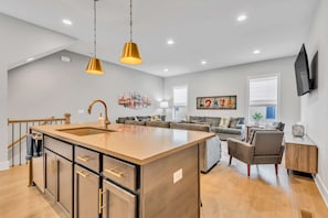 A modern kitchen with a central island, a dining area with a sofa, and a living room with a TV.