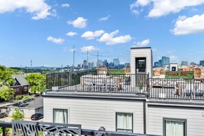 Tagterrasse med udsigt over byens skyline, inklusive et 'Music City' skilt, og et afspærret område med udendørs siddepladser.