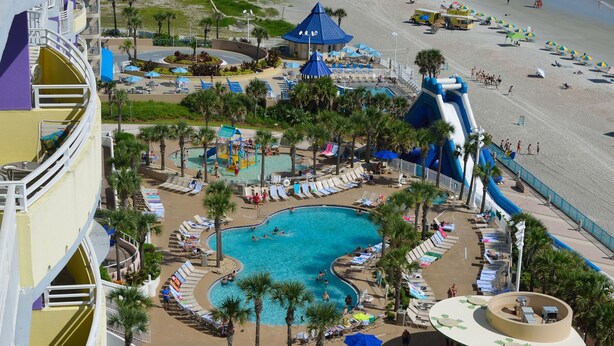 Un resort con una piscina grande, un tobogán acuático y una zona de playa.