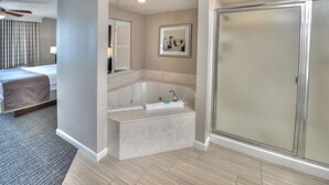 Un baño moderno con una bañera grande, cabina de ducha y un cuadro enmarcado en la pared.