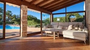 Una habitación amplia con un ventanal grande, una piscina, un sofá y una mesa de centro.