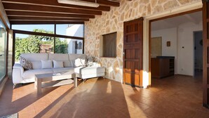 Un salón amplio con una pared de piedra, un sofá blanco, una mesa de centro de madera y un ventanal grande.
