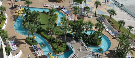 Un resort con varias piscinas, palmeras y tumbonas.