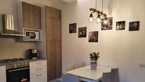 Eine moderne Küche mit Essbereich, ausgestattet mit einem weißen Tisch, Stühlen, einer Kaffeemaschine, einer Mikrowelle und einem Herd.