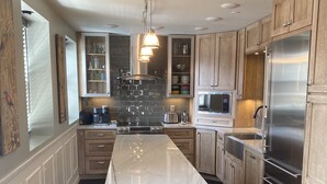 A modern kitchen with wooden cabinets, a marble countertop, a built-in oven, and a stainless steel refrigerator. - Loft on Mountain (in Old Town) (Fort Collins)