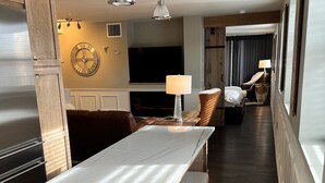 A hotel room with a marble dining table, a sofa, a TV, and a bed with a lamp. - Loft on Mountain (in Old Town) (Fort Collins)
