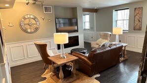 A living room with a fireplace, leather sofa, and a dining table with chairs. - Loft on Mountain (in Old Town) (Fort Collins)