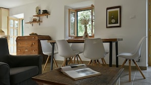 A dining area with a wooden table, white chairs, a sofa, and a dresser. - Villa Dol-Three Bedroom Villa with Pool (Postira)