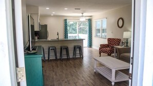 A kitchen with a bar area, a dining table, and a patterned armchair. - Paradise Vacation Rental with Water Views (Palm Harbor)