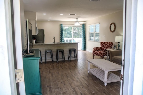 A kitchen with a bar area, a dining table, and a patterned armchair.