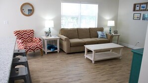 A living room with a beige sofa, patterned armchair, and a coffee table. There are two side tables with lamps. - Paradise Vacation Rental with Water Views (Palm Harbor)