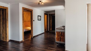 Un couloir doté d’un plancher en bois, de murs blancs et d’un luminaire au plafond.