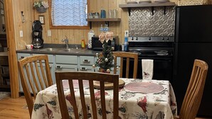 A cozy kitchen with wooden walls, a dining table with chairs, and a chandelier. - 1 Playful Cub-GREAT unbelievable rates, check it out (Cosby)