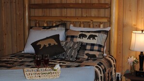 A wooden-paneled room with a bed, two bedside tables, and a nightstand. - 1 Playful Cub-GREAT unbelievable rates, check it out (Cosby)