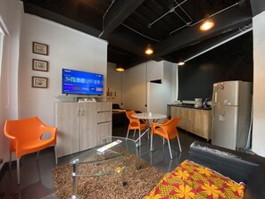 A modern kitchen with a refrigerator, a dining table with orange chairs, and a glass coffee table. - Full comfort loft apartment luxury design ChapAlto (Bogotá)