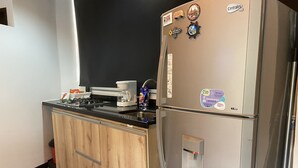 Una cucina compatta con frigorifero, macchina del caffè e fornello a gas.