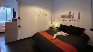 Una camera d'albergo moderna con un letto, una scrivania e una parete decorata con un'opera d'arte raffigurante un panorama urbano.