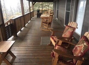 Une terrasse en bois avec une table et des chaises, une fenêtre et une porte.
