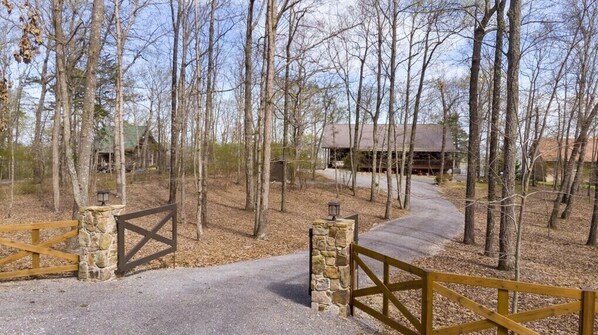 Une cabane rustique entourée d’arbres, une porte en pierre et une clôture en bois.
