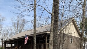 A cabin with a porch, an American flag, and daffodils in the yard. - 5⭐️ Breathtaking Bluff Views Serene 2 Bed/2Bath Brow Cabin Cloudland near Mentone (Cloudland)
