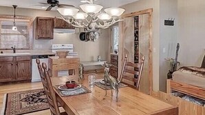 A dining area with a wooden table, chairs, a chandelier, and a ceiling fan. - 5⭐️ Breathtaking Bluff Views Serene 2 Bed/2Bath Brow Cabin Cloudland near Mentone (Cloudland)