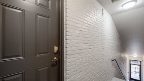 Una escalera con un muro de ladrillo blanco y una puerta de madera oscura.
