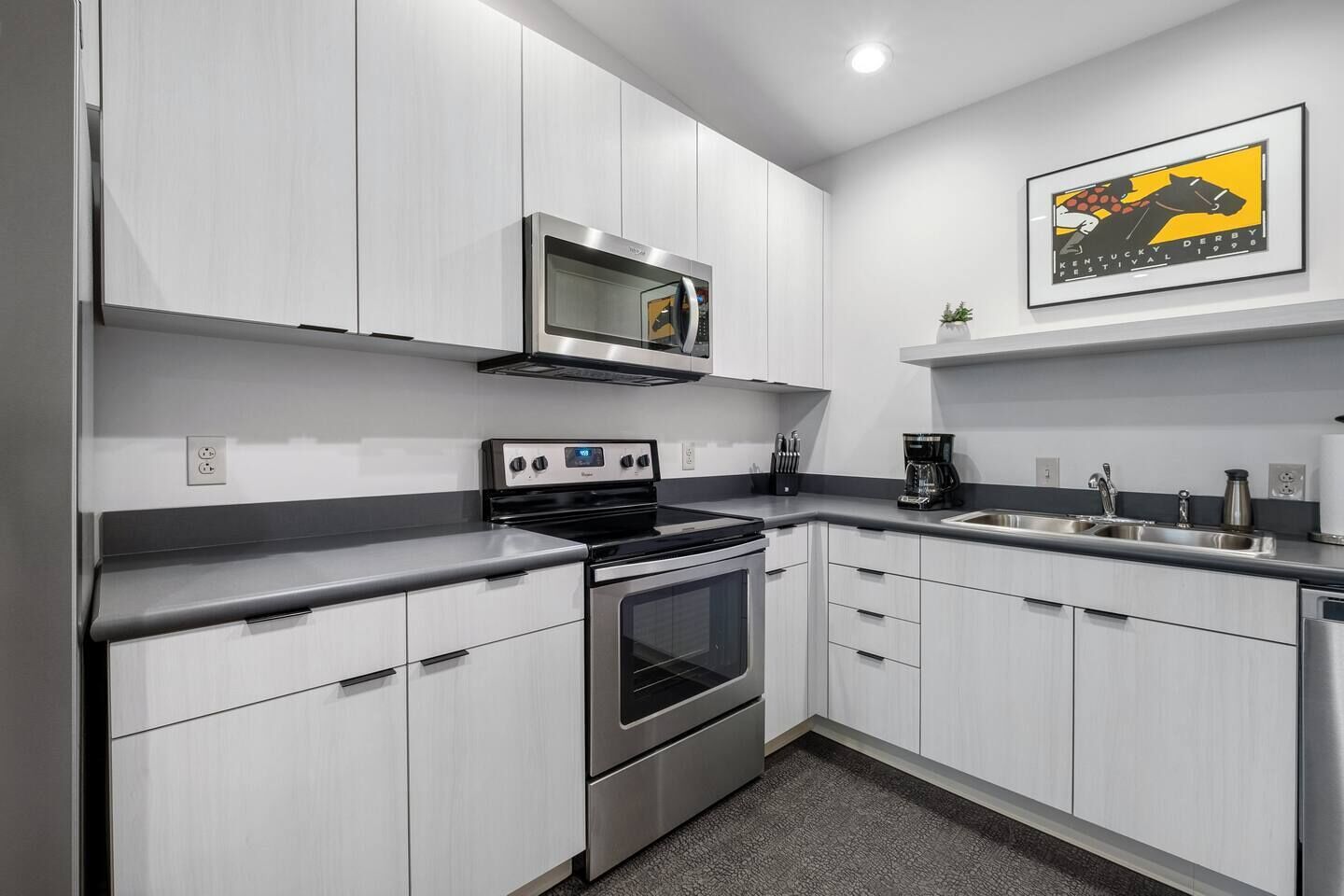 A modern kitchen with white cabinetry, stainless steel appliances, and a microwave above the stove.