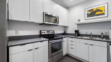 A modern kitchen with white cabinetry, stainless steel appliances, and a microwave above the stove.