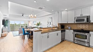 A modern kitchen with white cabinets, stainless steel appliances, and a large island. - Beautiful Condo with Golf Course Views, Near Attractions (Kissimmee)