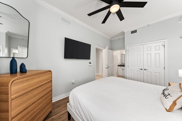 A bedroom with a bed, a dresser, a mirror, and a ceiling fan. - Beautiful Condo with Golf Course Views, Near Attractions (Kissimmee)