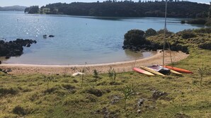 A beach with kayaks and a sailboat. - Northern Lodge - cottage in a quiet rural setting, lush tropical gardens (Kerikeri)