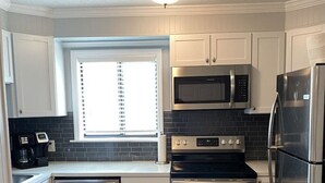 A compact kitchen with white cabinets, a microwave, a stove, and a refrigerator. - Steps away from the BEACH! (Hilton Head Island)