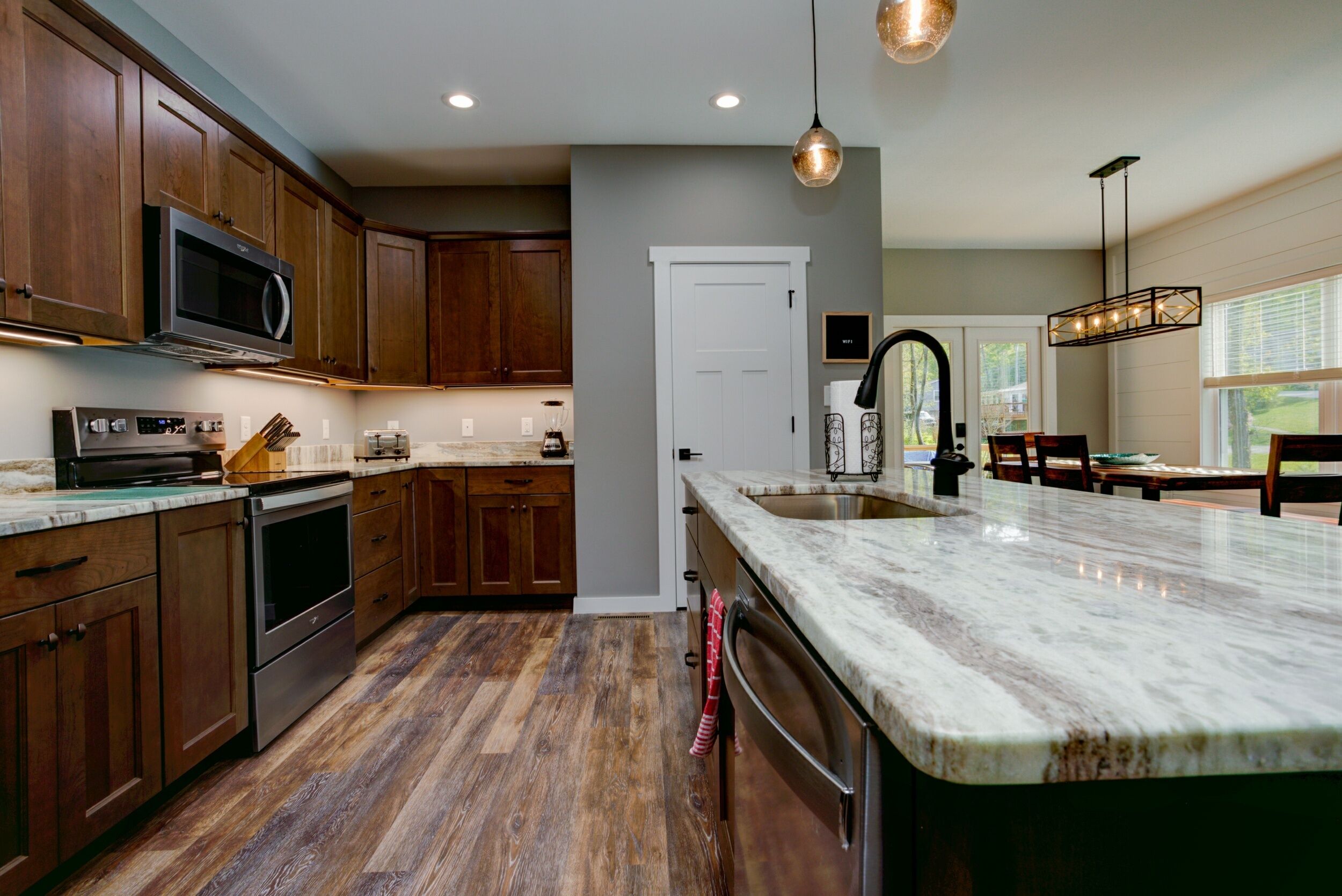 Una cocina moderna con armarios de madera, microondas integrado, electrodomésticos de acero inoxidable y una isla grande con fregadero.