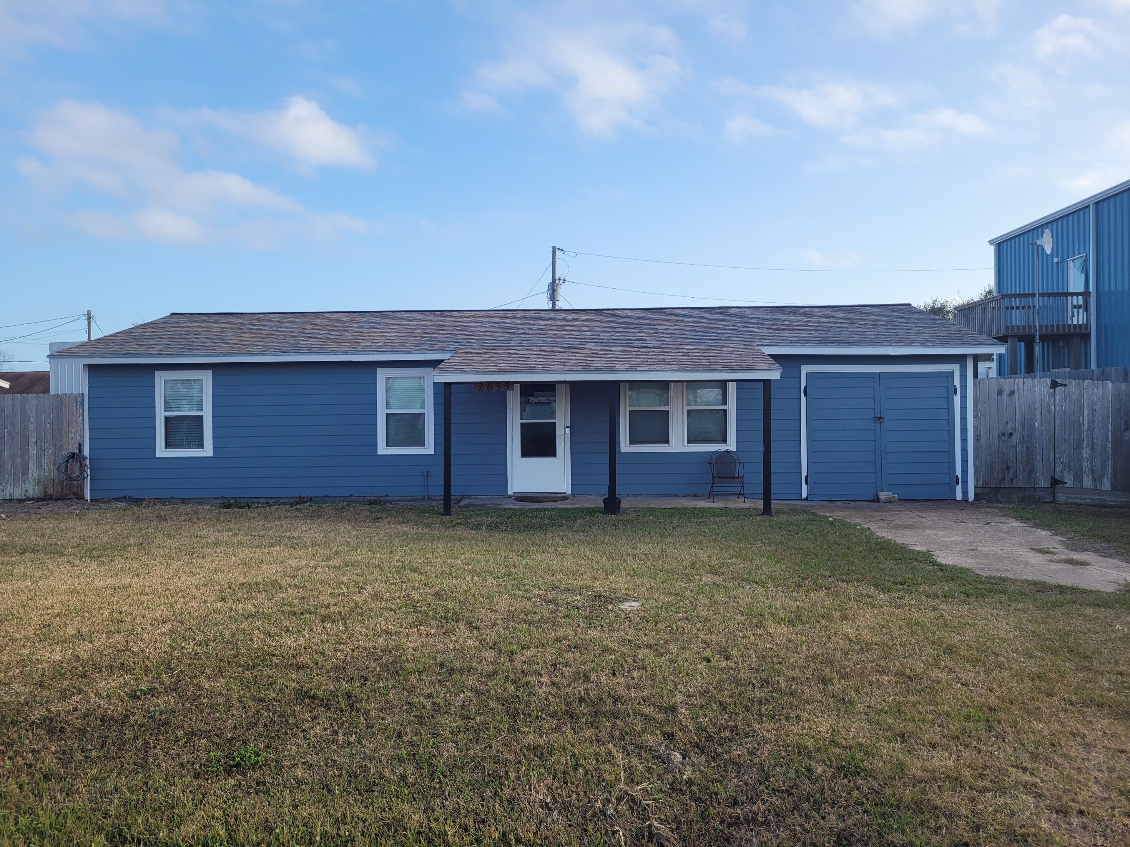 A single-story house with a front porch, a garage, and a fenced yard.