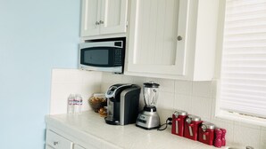 A kitchen with white cabinets, a microwave, a blender, and red salt shakers on the counter. - Beach house with unforgettable view (Los Angeles)