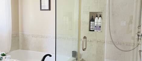 A bathroom with a glass-enclosed shower, a bathtub, and a sink with a faucet.