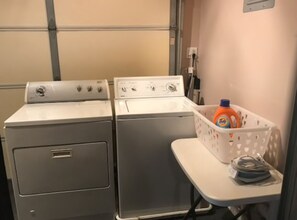 A laundry area with two washing machines and a basket containing laundry detergent. - Beach house with unforgettable view (Los Angeles)