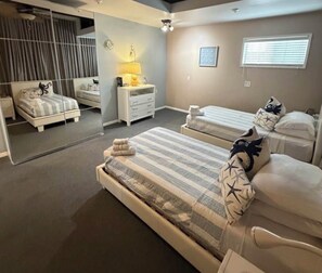 A bedroom with two beds, a dresser, a mirror, and a window with blinds.