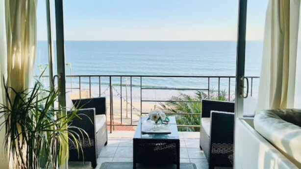 A balcony with a view of the sea, a table with a plant, and two chairs. - Beach house with unforgettable view (Los Angeles)