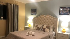 A bedroom with a tufted headboard, two bedside lamps, and a neatly made bed with a folded towel. - Beach house with unforgettable view (Los Angeles)