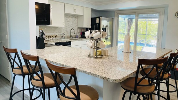 Een moderne keuken met een groot eiland, barkrukken en uitzicht op de omgeving.